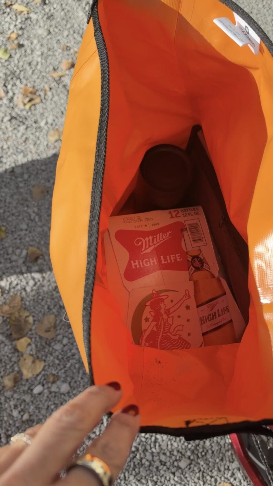 Open orange ROCKBROS pannier holding a Miller High Life 12-bottle package.